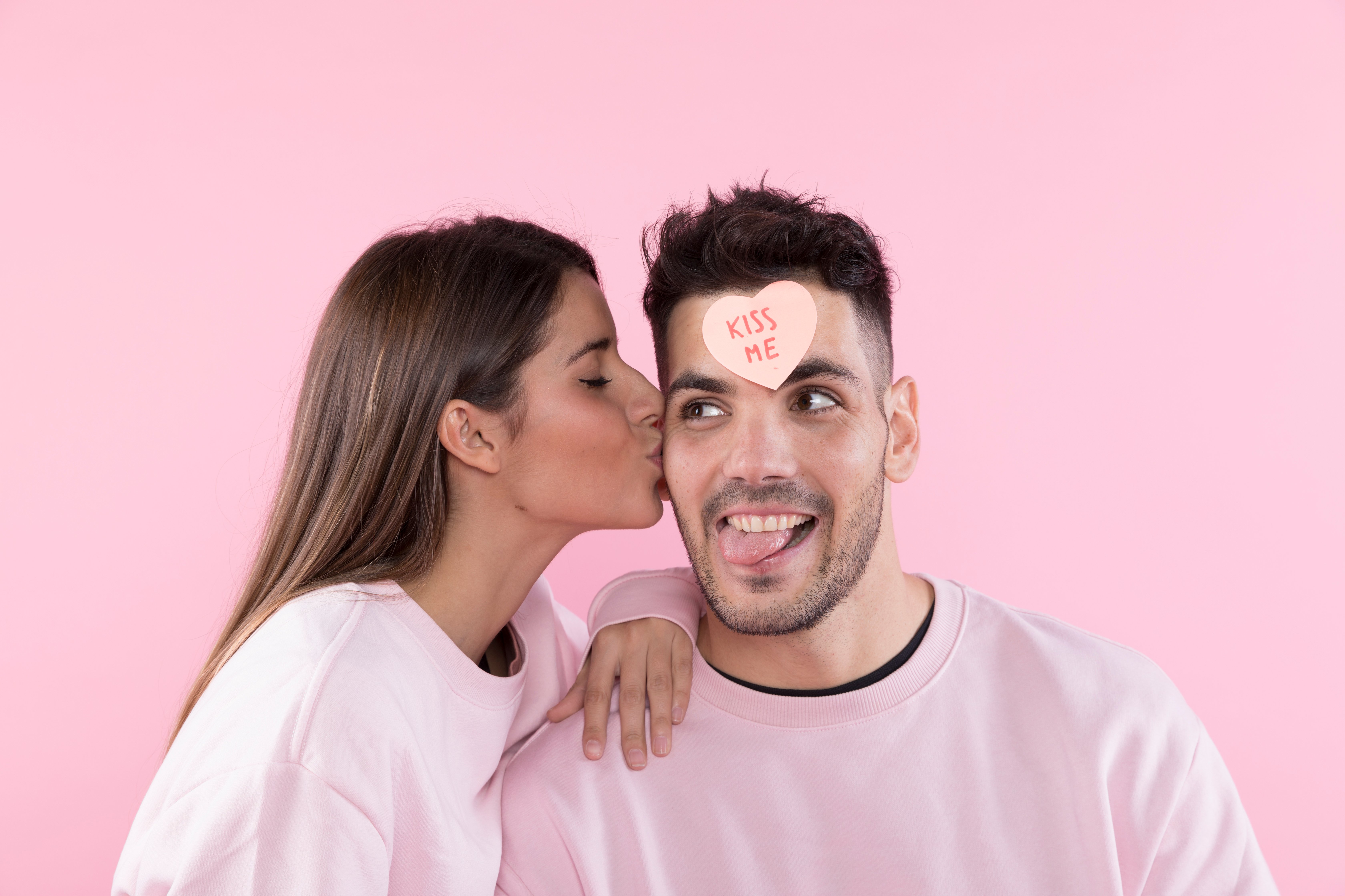 woman-kissing-young-man-with-paper-heart-front